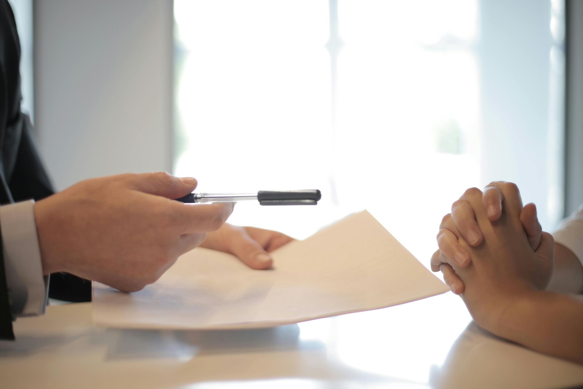 An attorney handing a pen to a client to sign paperwork across a desk